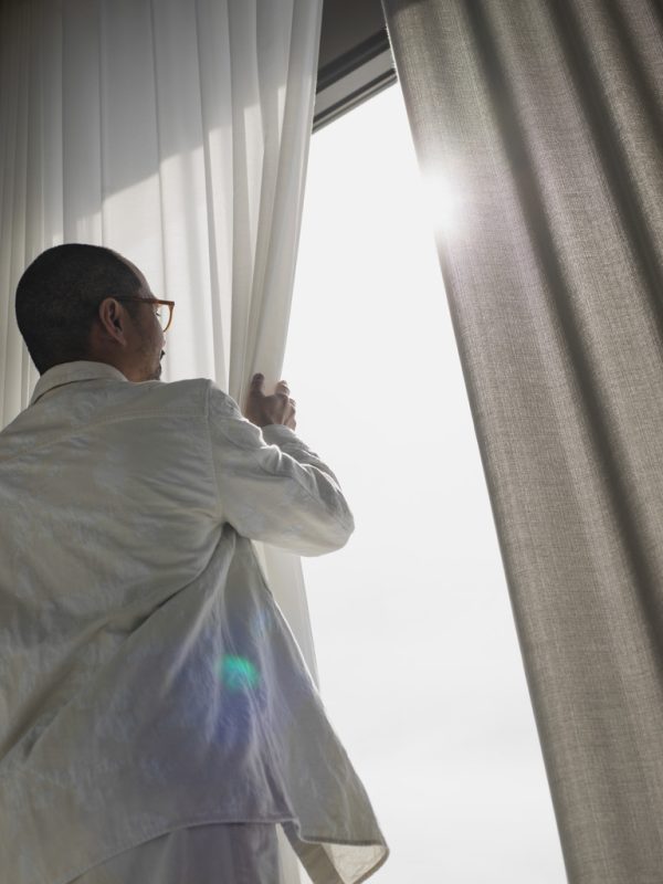 A man holding up Almedahls Circle curtains, highlighting fabric transparency.