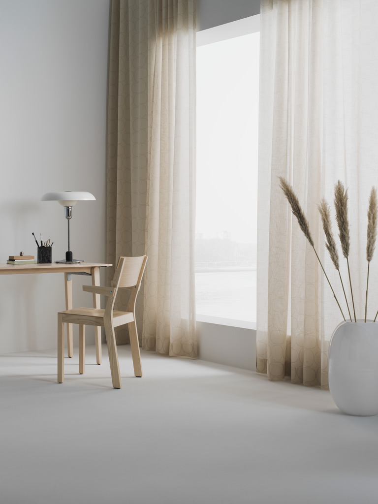 Inspiro curtains in soft beige from the Piet Hein collection, hanging gracefully in a modern, minimalist room.