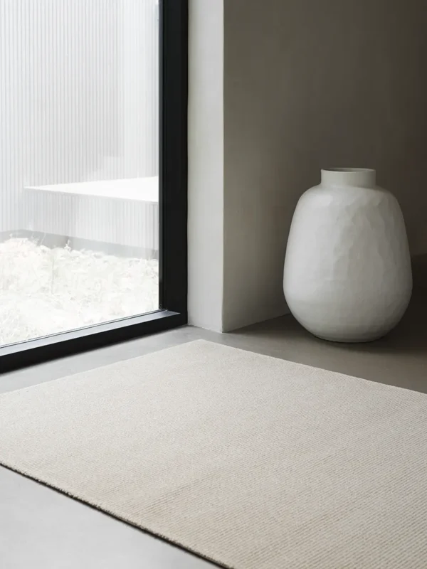 Photo of our rug Sow from our Field collection, next to a window.