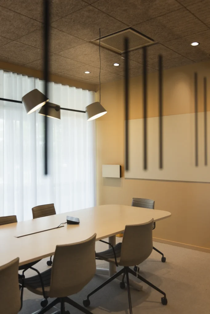 Ett mötesrum med akustiktakpaneler och ett mjukt dagsljus som strömmar in genom gardinerna.